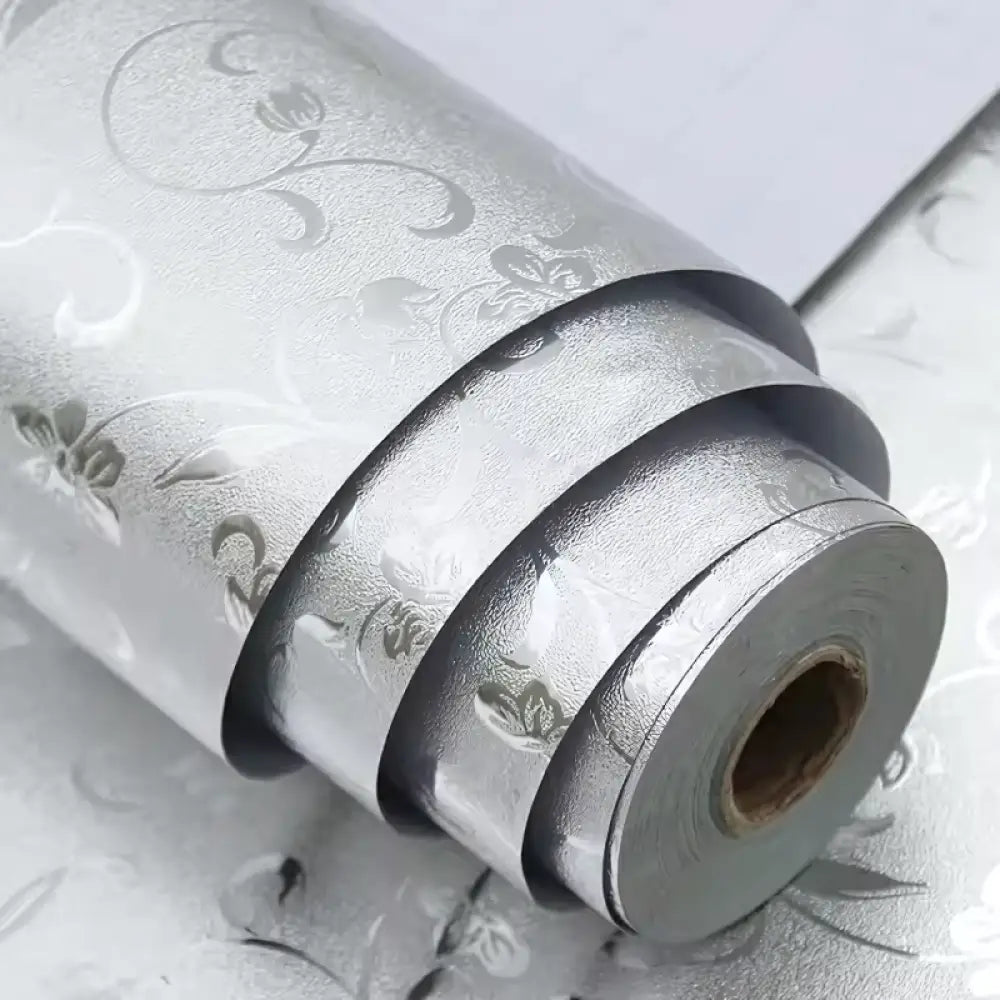 Rolo de papel de parede decorativo prateado com um padrão floral em relevo.