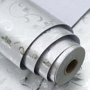 Rolo de papel de parede decorativo prateado com um padrão floral em relevo.