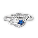 Anel de prata com uma pedra preciosa azul em forma de estrela cercada por pequenos diamantes em um design circular.