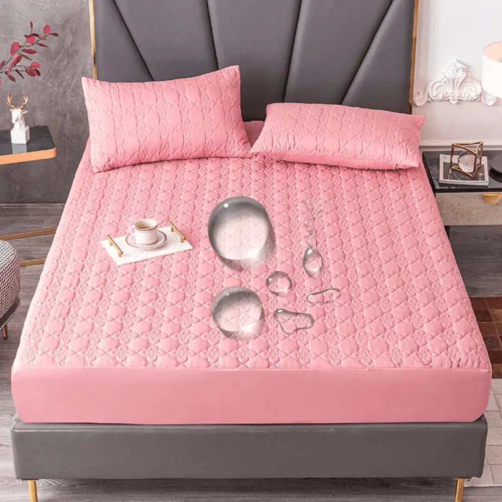 Protetor de colchão rosa acolchoado à prova d’água com fronhas combinando em uma cama.