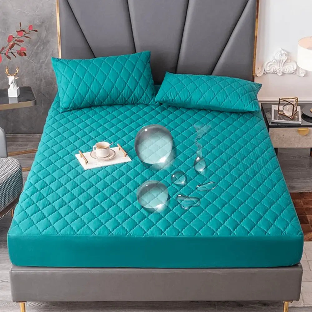 Capa de colchão acolchoada à prova d’água na cor azul-petróleo com fronhas combinando em uma cama.