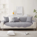 Sofá em dois tons com almofadas cinza em uma base branca.