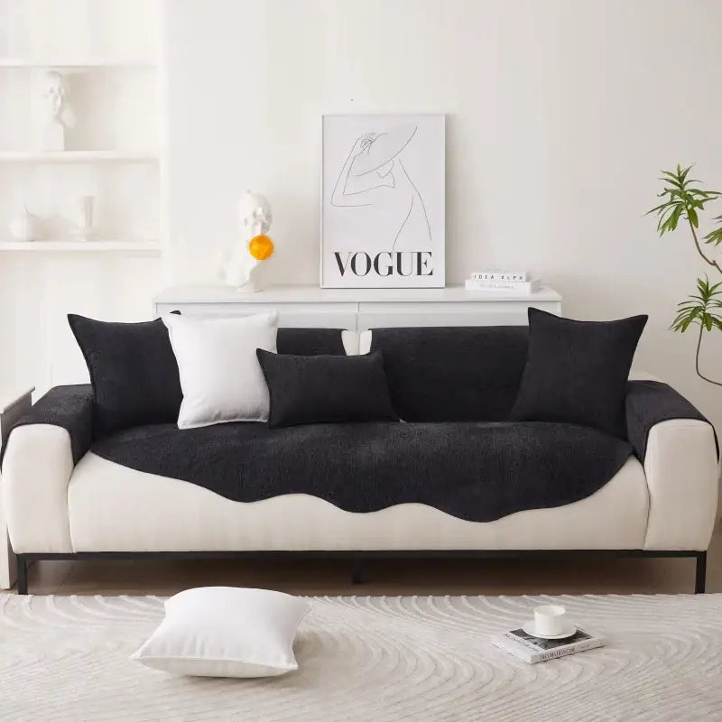 Sofá em dois tons com almofadas pretas e base branca.