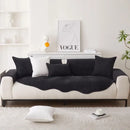 Sofá em dois tons com almofadas pretas e base branca.