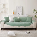 Sofá branco com uma capa verde e travesseiros verdes combinando.