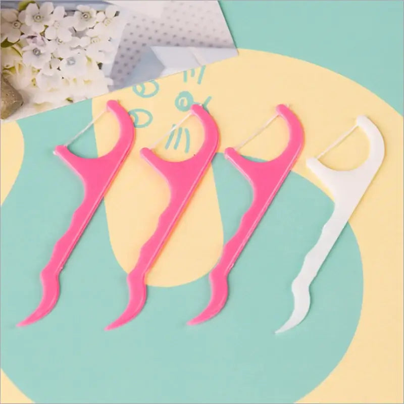 Palitos de fio dental nas cores rosa e branco.