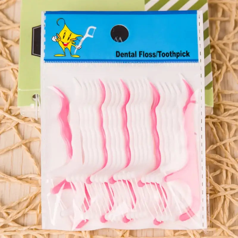 Pacote de fio dental/palitos de dente de plástico rosa com um personagem de desenho animado no rótulo.