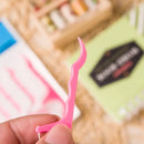 Palito de fio dental de plástico rosa segurado entre os dedos.