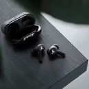 Par de fones de ouvido sem fio pretos com o estojo de carregamento.