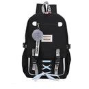 Mochila preta com alças decorativas, patches e um acessório de pompom fofo.