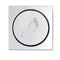 Botão circular de metal com um desenho de pegada gravado.