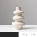 Vaso de cerâmica branca com uma silhueta curvilínea e ondulada.